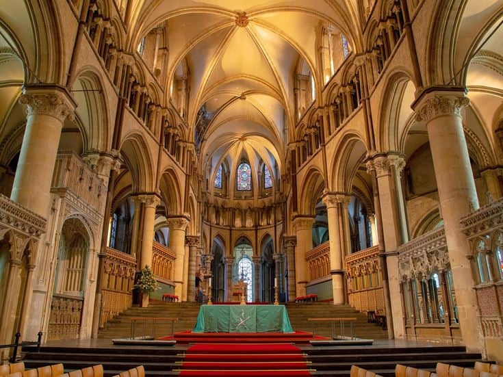Inside Canterbury Cathedral, with an altar and red carpet.