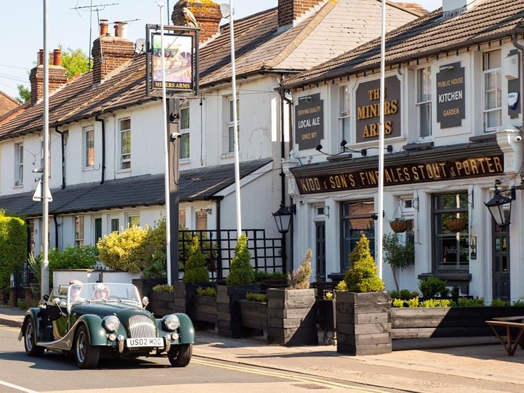 A retired couple sit in their classic car outside The Miners Arms pub in Dunton Green.