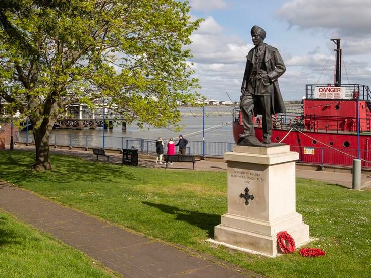 a statue of a person on a pedestal by a body of water