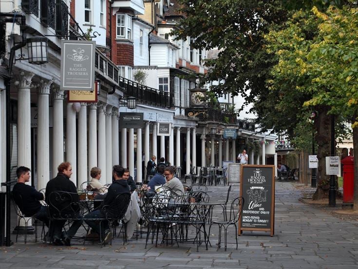 People sitting at tables outside with The Pantiles in the background