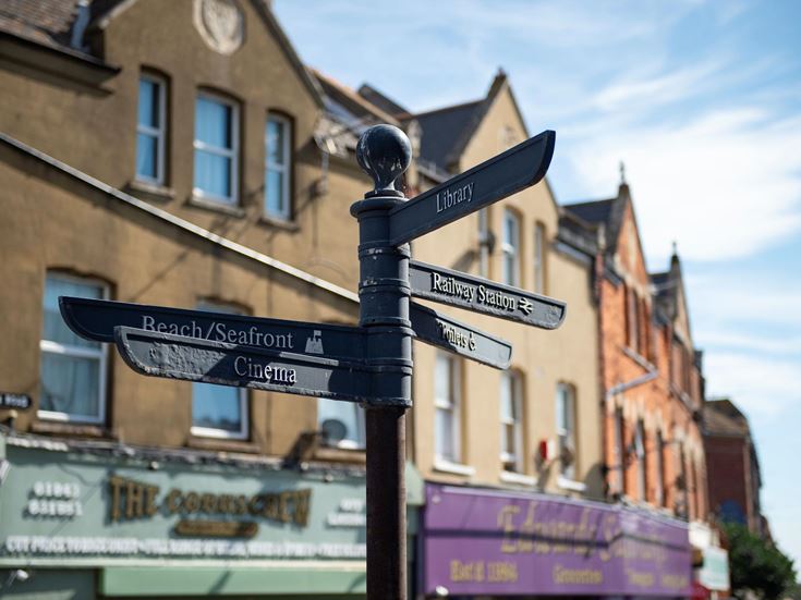 A signpost in Westgate-on-Sea pointing people to the railway station, library, and seafront.