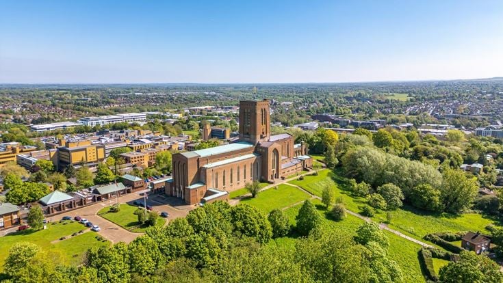 Aerial view of Guildford Cathedral overlooking Guildford town centre and the surrounding Surrey countryside.