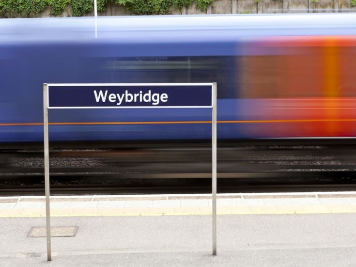 A train on the railway tracks passing through Weybridge train station.