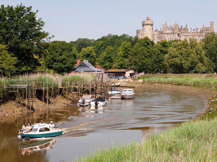 A river full of boats with a Arundel Castle in the background.