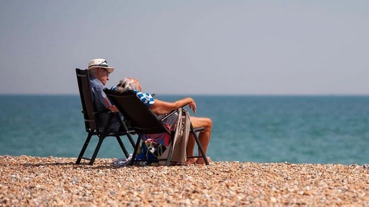 a man and woman sitting in chairs on a beach