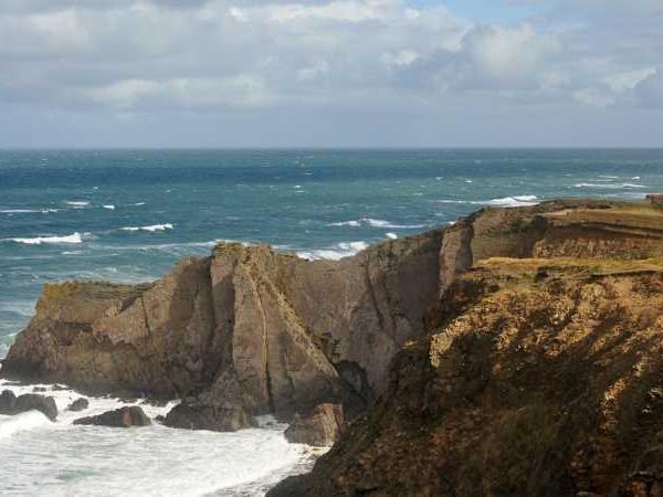 a rocky cliff with a body of water in the background