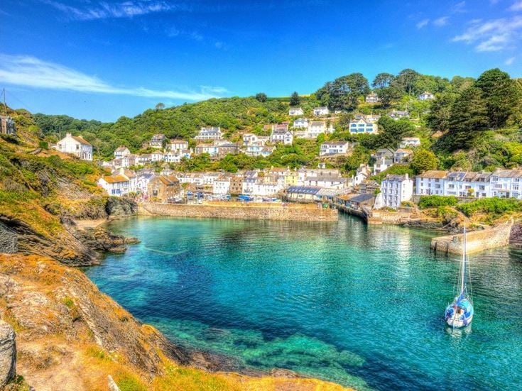 The coastal village of Polperro, Cornwall, surrounded by clear water and sailboats.