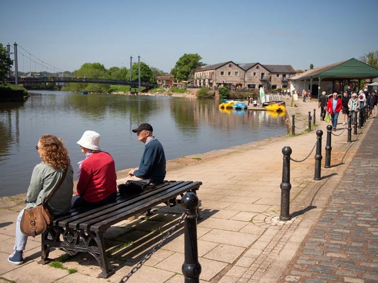 people sitting on a bench by a river