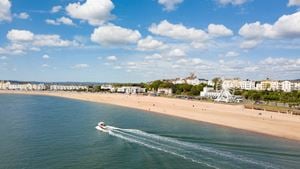 The seafront in Exmouth, with a boat and a green fields across the bay