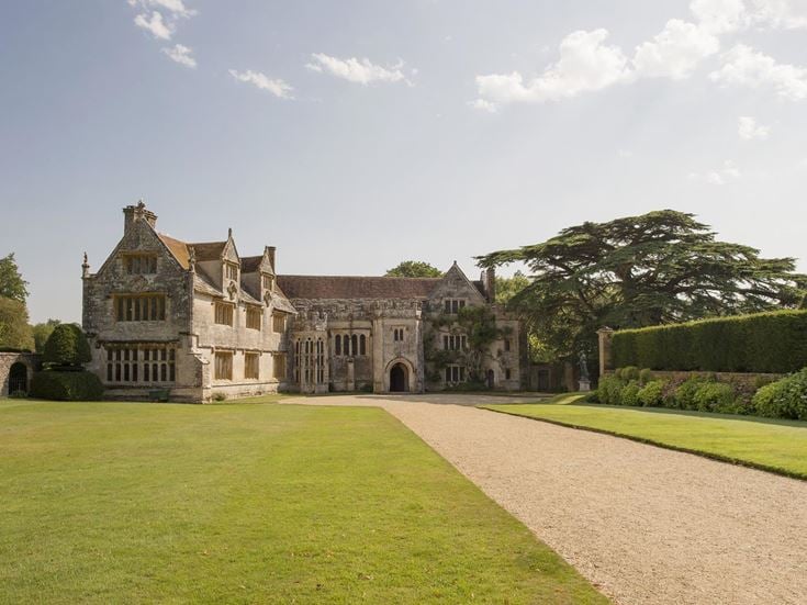 Athelhampton House, a large house with a lawn and hedges in front of it with Athelhampton in the background