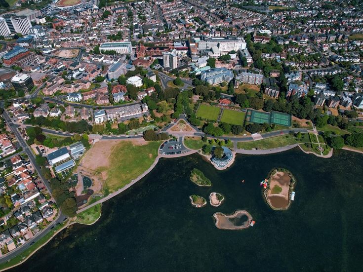 Aerial photograph of Poole Park showcasing its lakeside setting, sports facilities and open green space.