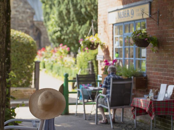A retired person sits at a table in front of Number 9 cafe in Wimborne Minster, Dorset.