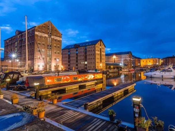Canal boats and brick buildings in Gloucester Docks at dusk.