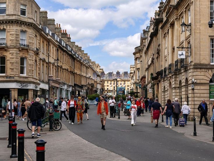 a group of people walking on a street between buildings