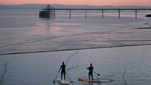 Paddleboarders in front of Clevedon pier at sunrise