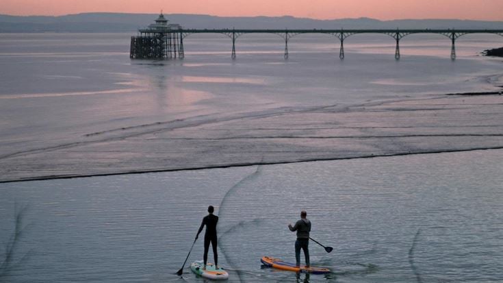Paddleboarders in front of Clevedon pier at sunrise