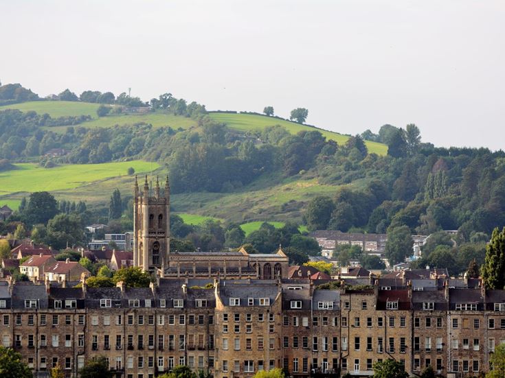 a large green hillside with buildings and trees