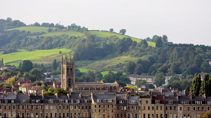 a large green hillside with buildings and trees