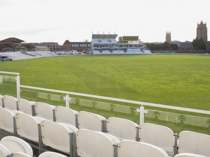 A view of Somerset Country Cricket ground from a row of white seats.