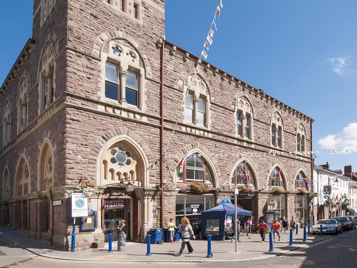 People walk outside Borough Theatre and Market Hall in Abergavenny, Wales.
