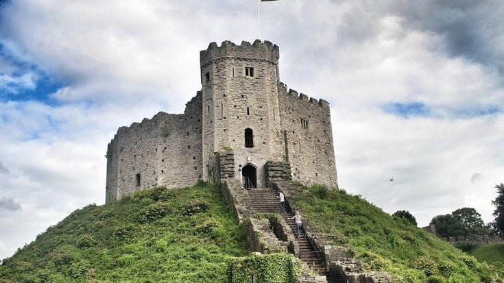 a stone castle on a hill with Cardiff Castle in the background