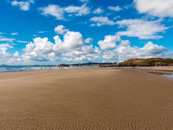 A sandy beach with blue sky and clouds.