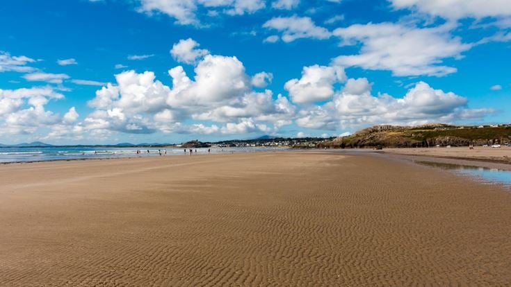 A sandy beach with blue sky and clouds.
