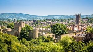 An aerial view of Ludlow Castle and surround town buildings and rolling hills in Shropshire.