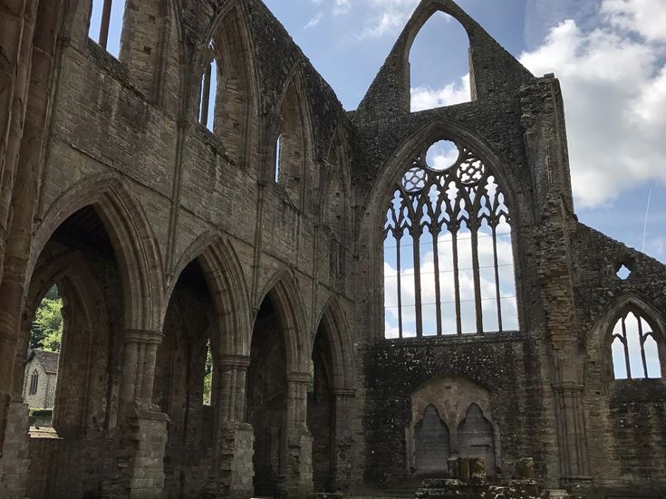 a large stone building with Sweetheart Abbey in the background