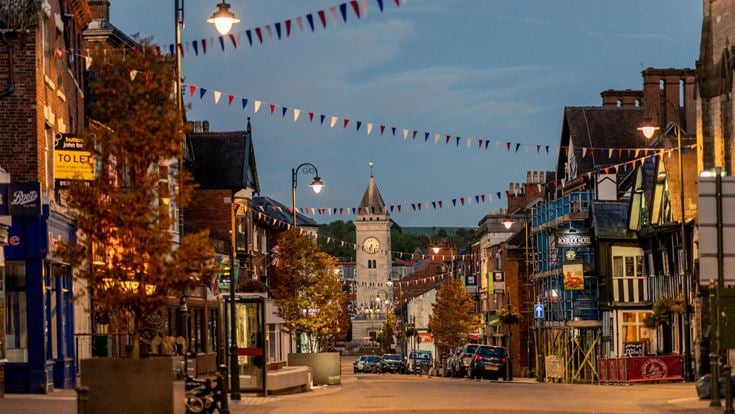 a street with buildings, trees on the side and bunting at dusk