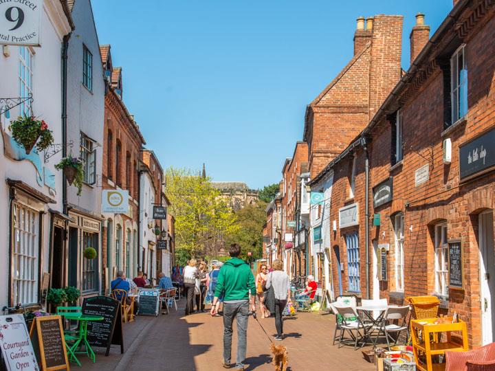 People walking down a street lined with cafés, shops, and boutiques.