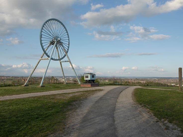 a road with grass and a truck on it and a large ferris wheel in the background