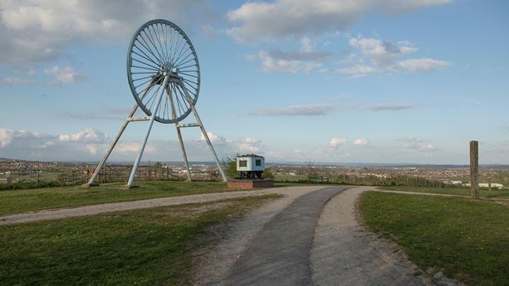 a road with grass and a truck on it and a large ferris wheel in the background