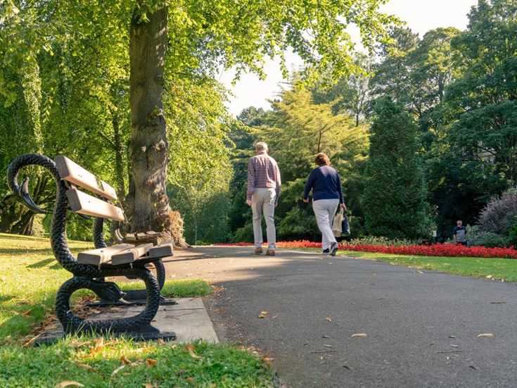 Two seniors enjoying a stroll through a green park in Harrogate.