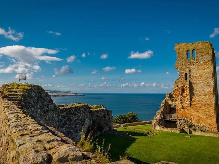 A stone wall and tower on a cliff at Scarborough Castle.