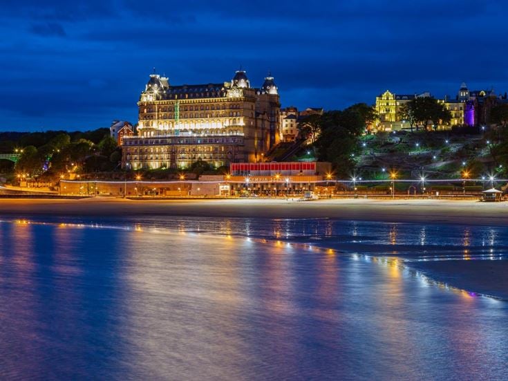 Scarborough South Bay at night with seafront buildings and amusements in lights.