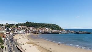 A view across South Bay Beach with people on it and Scarborough town buildings in the background.