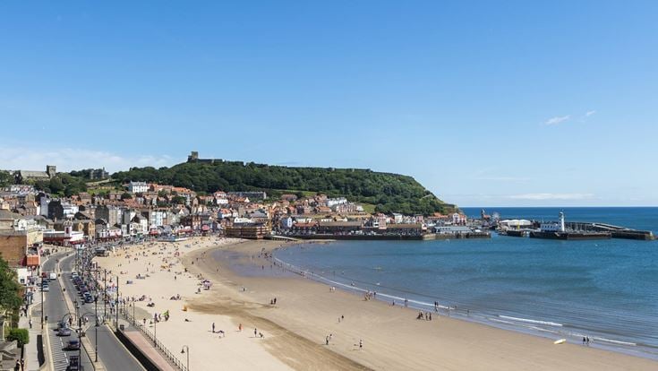 A view across South Bay Beach with people on it and Scarborough town buildings in the background.
