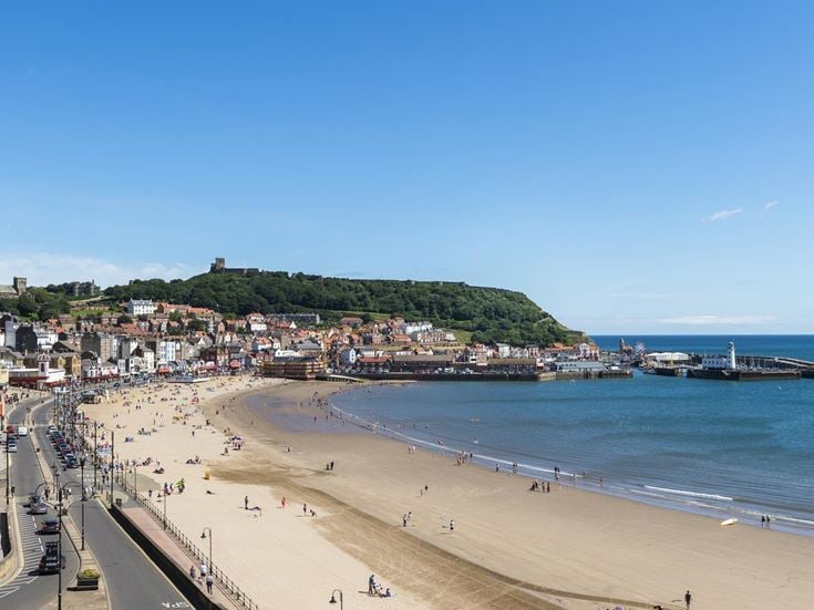 A view across South Bay Beach with people on it and Scarborough town buildings in the background.