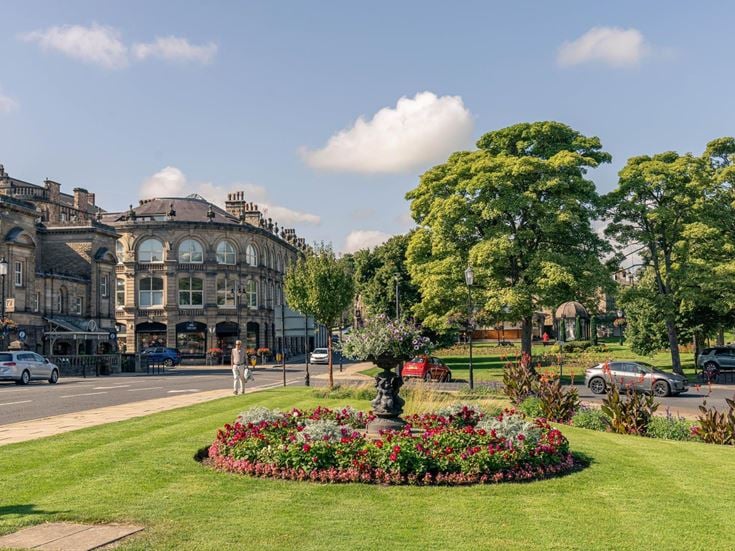 a large building with trees and flowers in front of it
