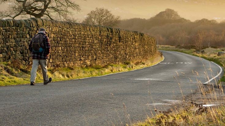 A retiree strides out for a sunny early morning walk along the road across Baildon Moor.