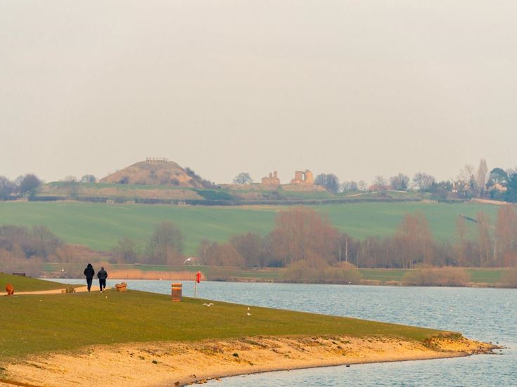 a grassy area with a body of water and a hill in the background
