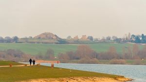 a grassy area with a body of water and a hill in the background