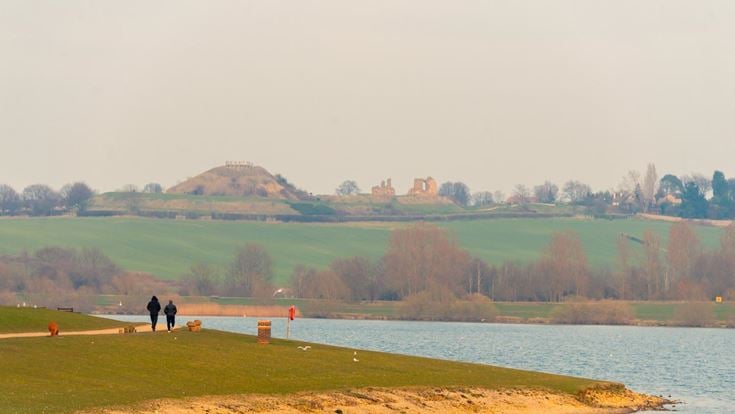 a grassy area with a body of water and a hill in the background