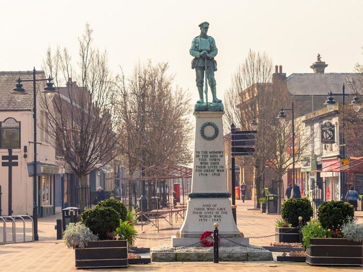 a statue of a person with a hat on a pedestal in a town