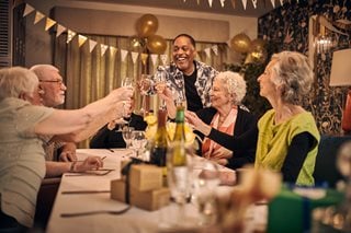 A group of retirees gathered around a table, toasting in celebration. 