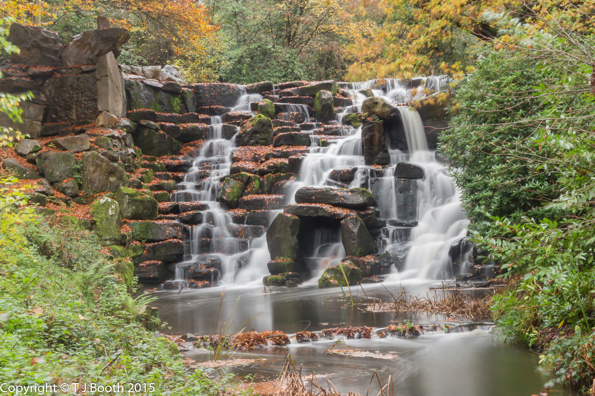 a waterfall with rocks and trees around it