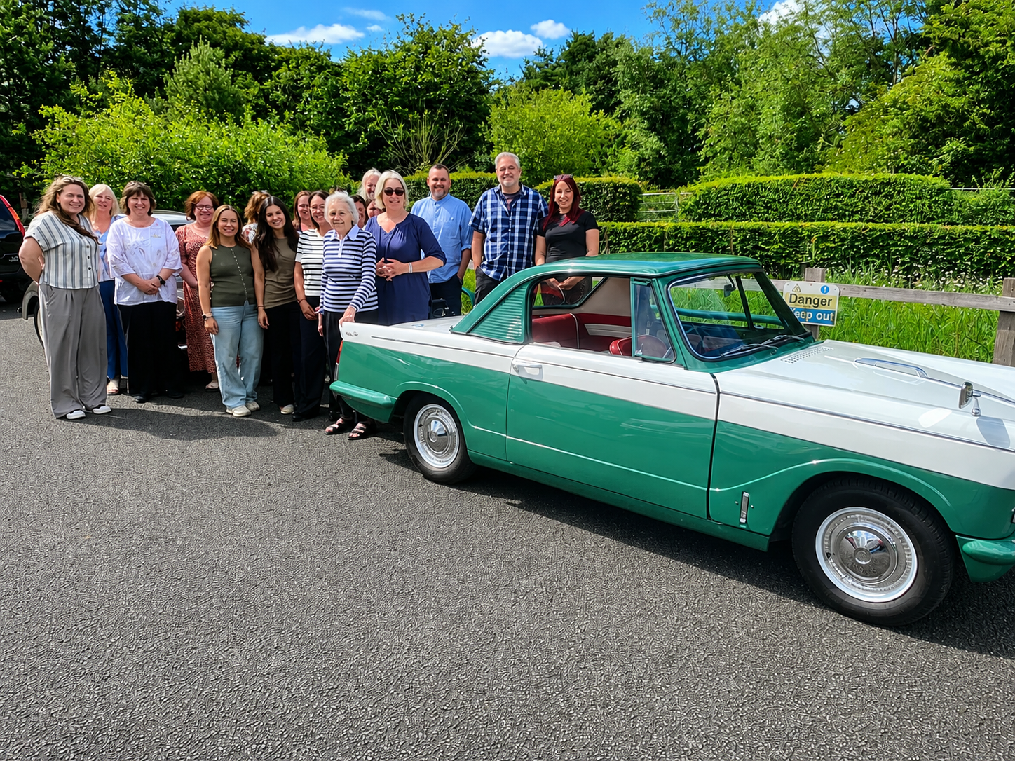 a group of people standing next to a green car