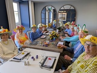 a group of people sitting at a table wearing hats