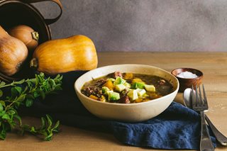 a bowl of soup next to a couple of pumpkins